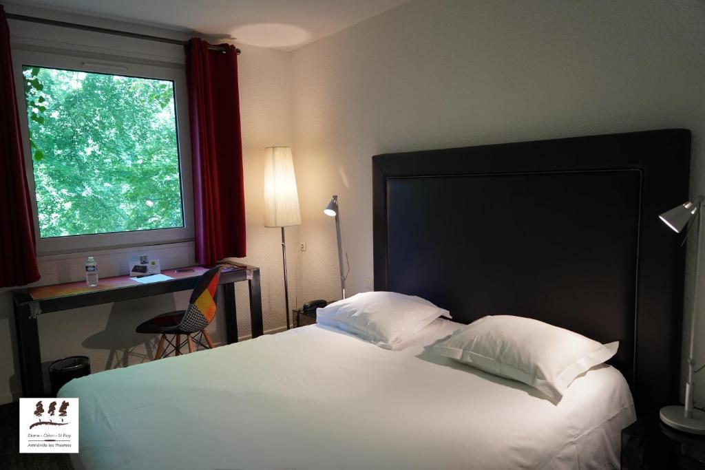 
a bedroom with a bed and a tv at Logis Hôtel Orion in Amnéville
