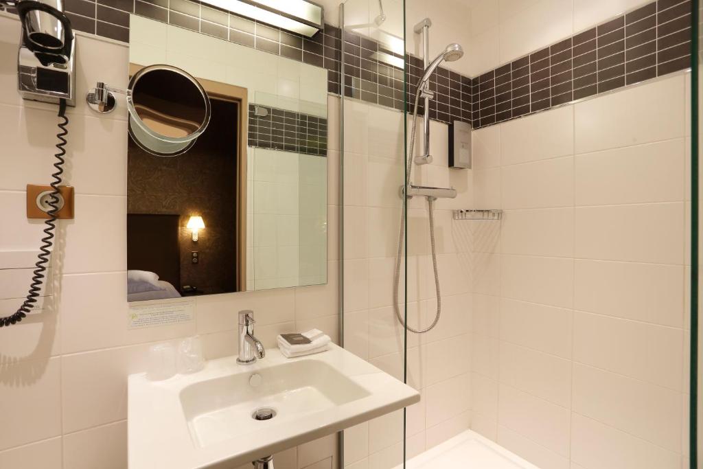 a white bathroom with a sink and a shower at Hôtel de Paris in Besançon