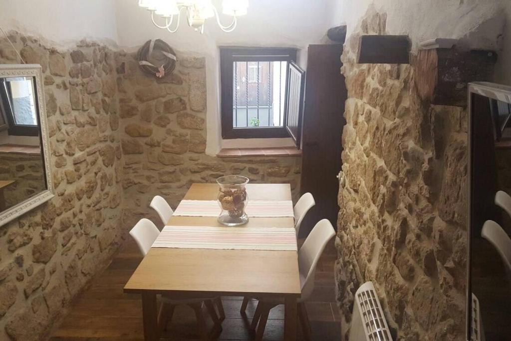 a wooden table in a room with a stone wall at El Encanto de Mora in Mora de Rubielos