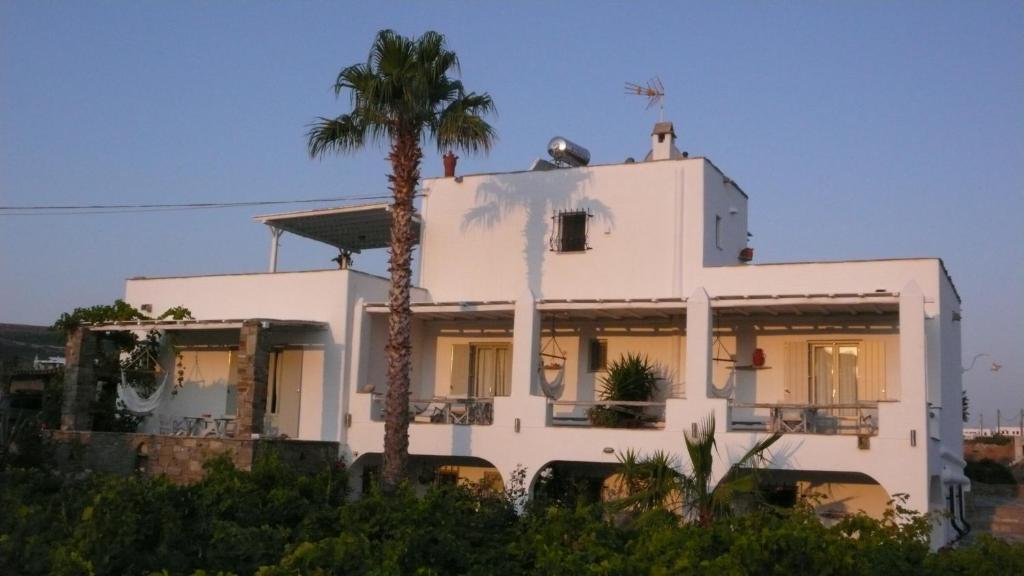 a white house with a palm tree in front of it at Paros Apartments in Parikia