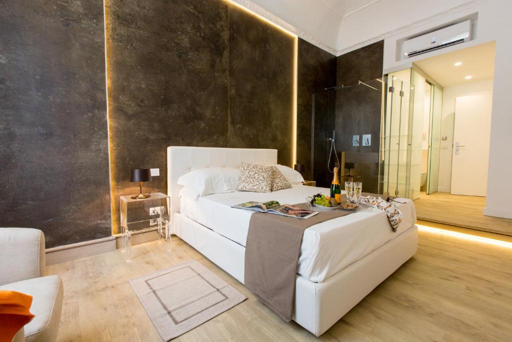 Palermo In Suite Aparthotel في باليرمو: غرفة نوم بسرير ابيض كبير واريكة