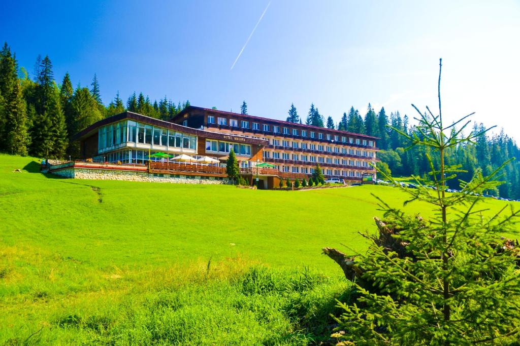 a large building on a grassy field in front at Hotel Magura in Ždiar