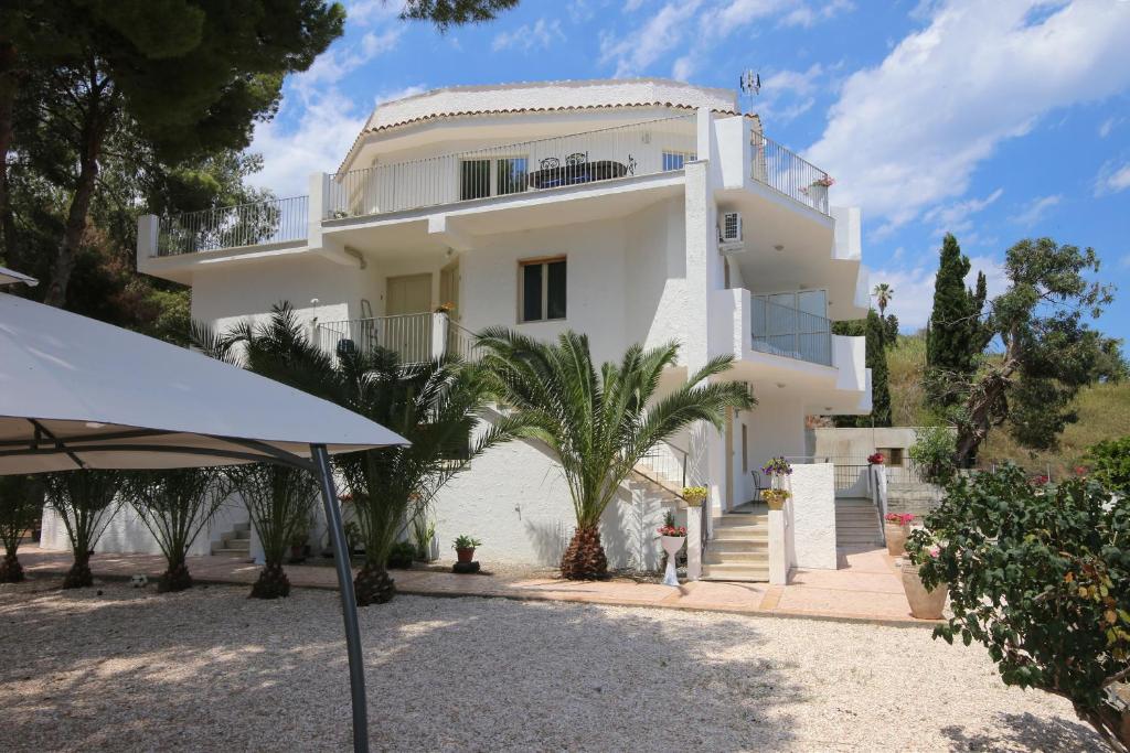 une grande maison blanche avec des arbres devant elle dans l'établissement villa aurora, à Giardini Naxos