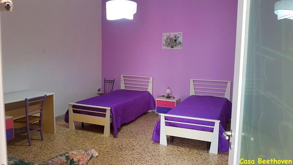 2 Betten in einem Zimmer mit lila Wänden in der Unterkunft La casa di Beethoven in Acquarica del Capo