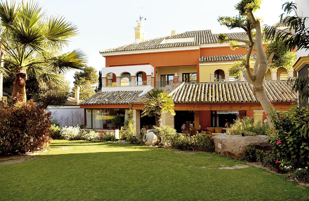 a large orange house with palm trees and a yard at Apartamentos Soho Boutique Vistahermosa in El Puerto de Santa María
