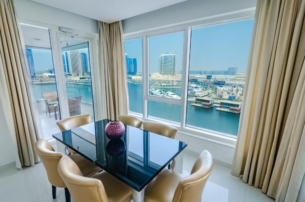 a dining room with a table and chairs and a large window at OSKENA Vacation Homes - Waterfront Downtown in Dubai