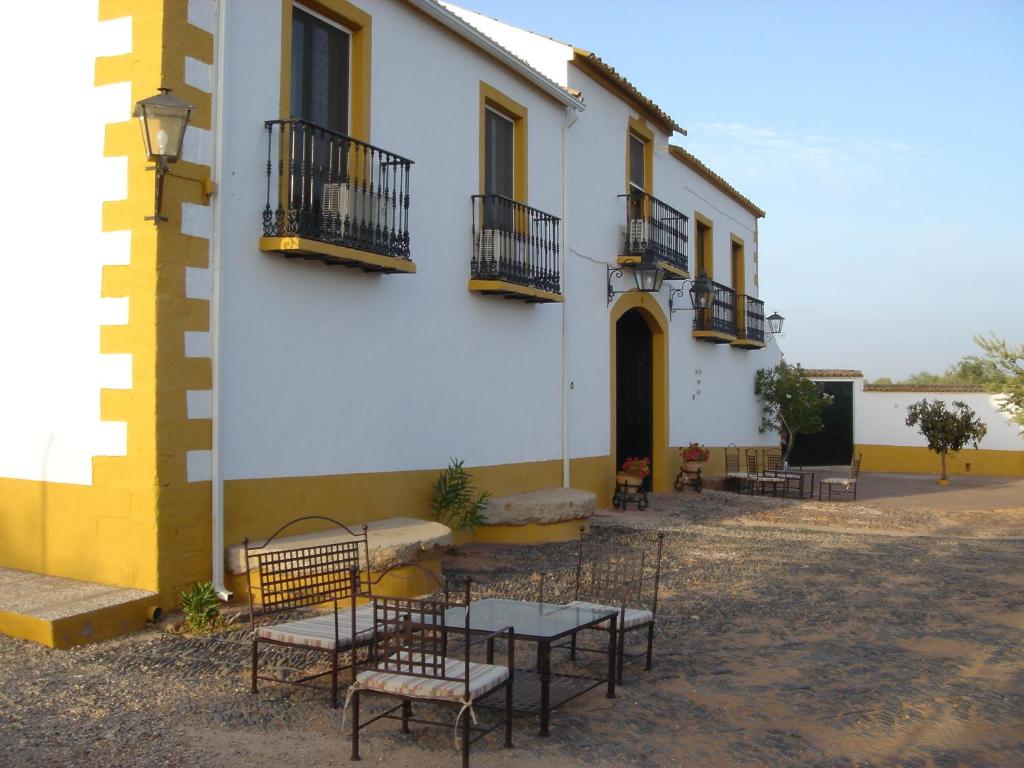 um grupo de mesas e cadeiras em frente a um edifício em Cortijo Molino San Juan em Montoro