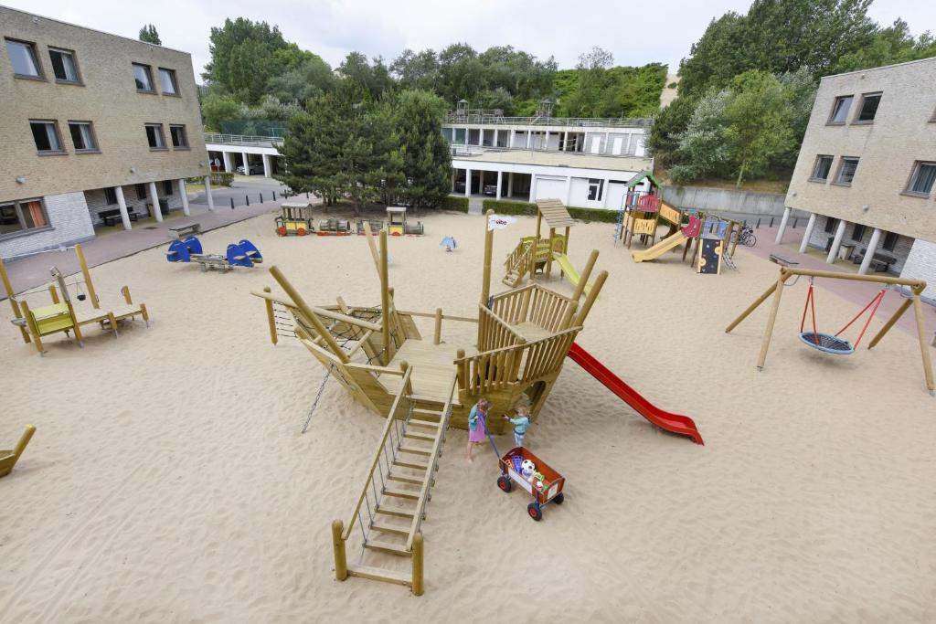 een lege speeltuin met een glijbaan en een rode glijbaan bij Vakantiedomein Hoge Duin in Oostduinkerke