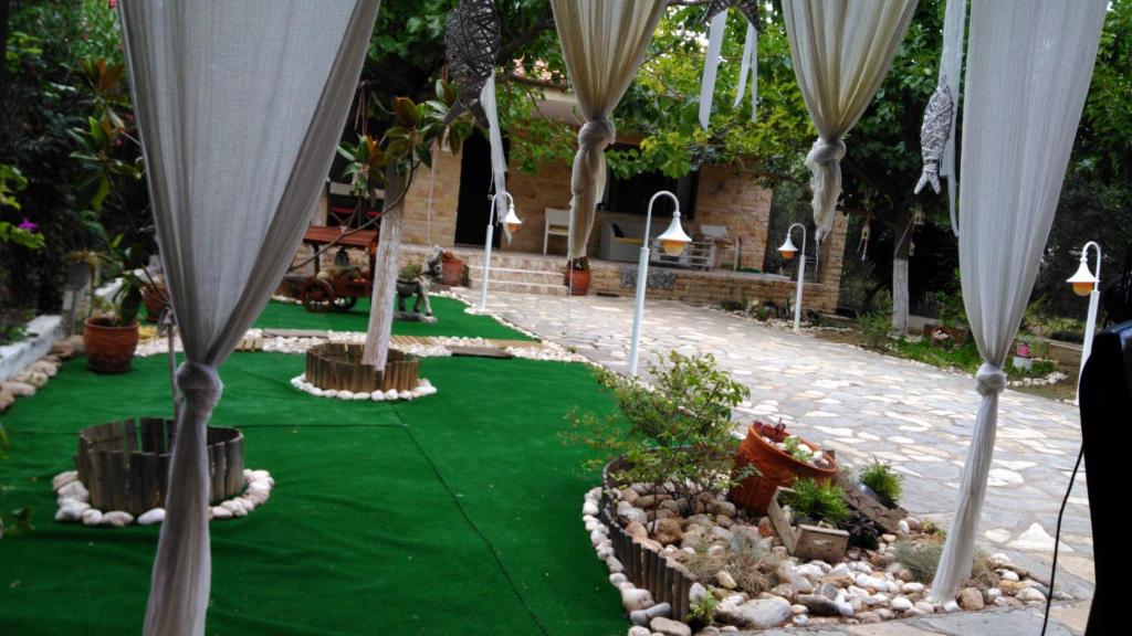 a garden with green grass and white umbrellas at ATHINA'S HOUSE in Nea Potidaea