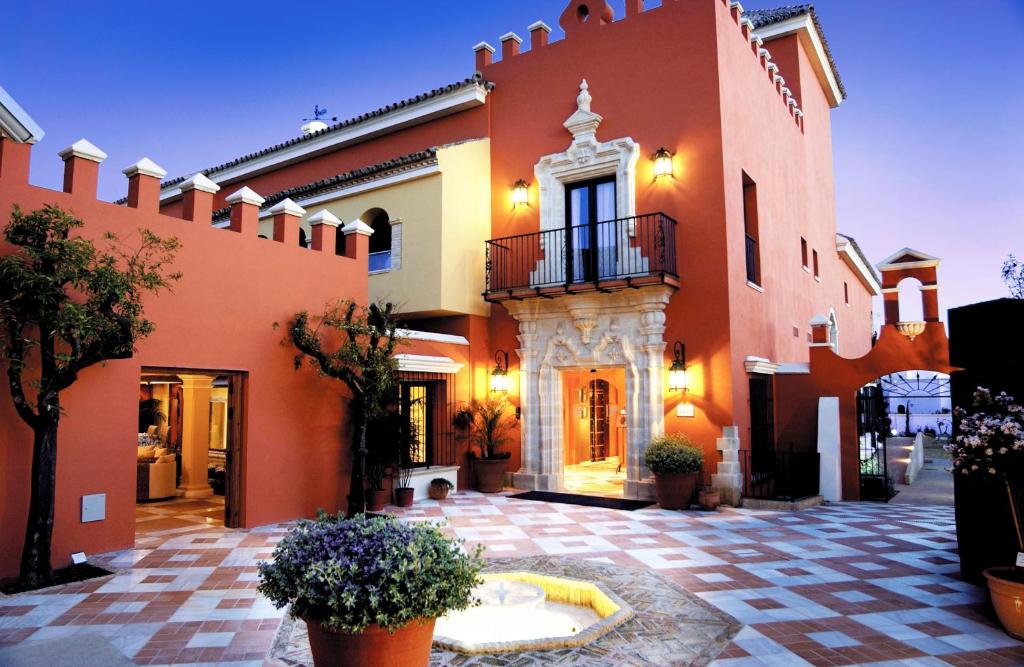 a large orange building with a courtyard with potted plants at Hotel Soho Boutique Vistahermosa in El Puerto de Santa María