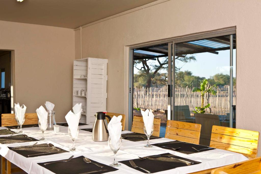 einen Esstisch mit weißen Tischdecken und Servietten in der Unterkunft Sesfontein Guesthouse in Sesfontein