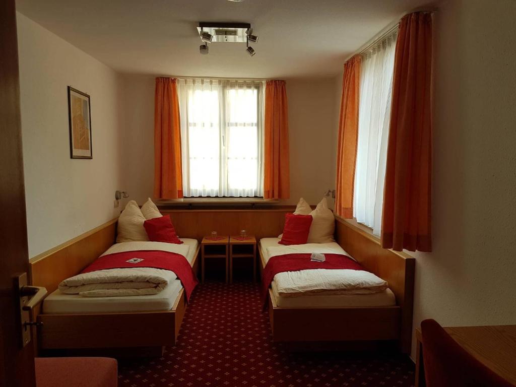 two beds in a hotel room with red curtains at Hotel Traube in Sigmaringen