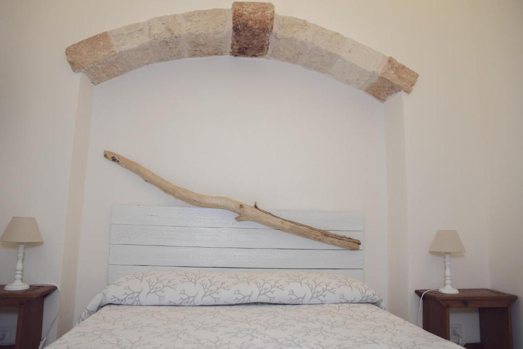 a bedroom with a bed with a branch on the wall at CASA MELIO' in Polignano a Mare