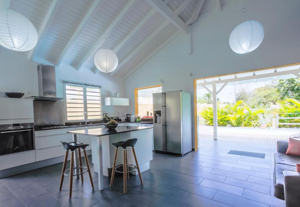 a kitchen with a refrigerator and some bar stools at Villa Bel Plaisi in Le Moule