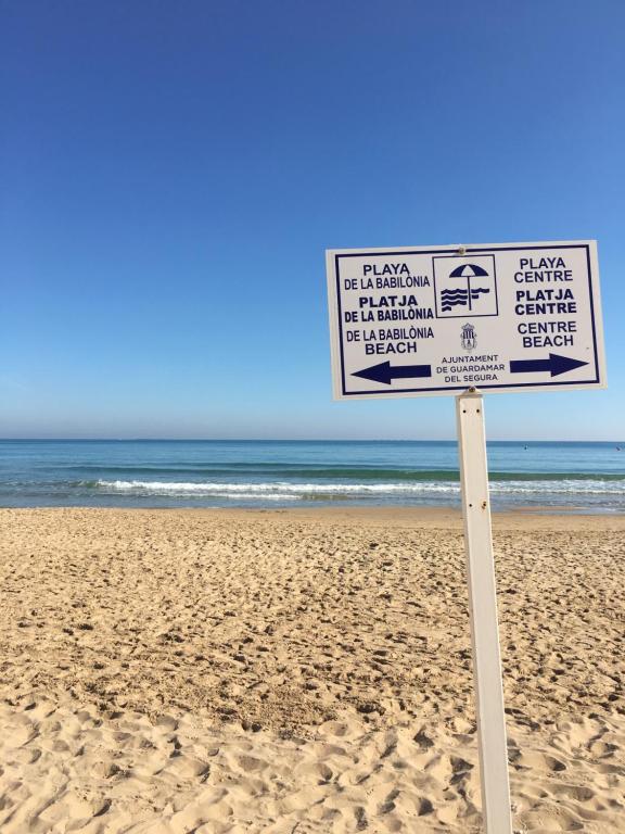 un cartel en una playa con el océano en el fondo en Apartamento playa Guardamar del Segura, en Guardamar del Segura