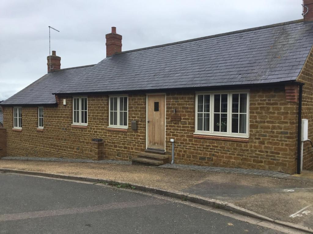 a brick house with a wooden door on a street at Upper Bray Cottage Badby, Daventry in Badby