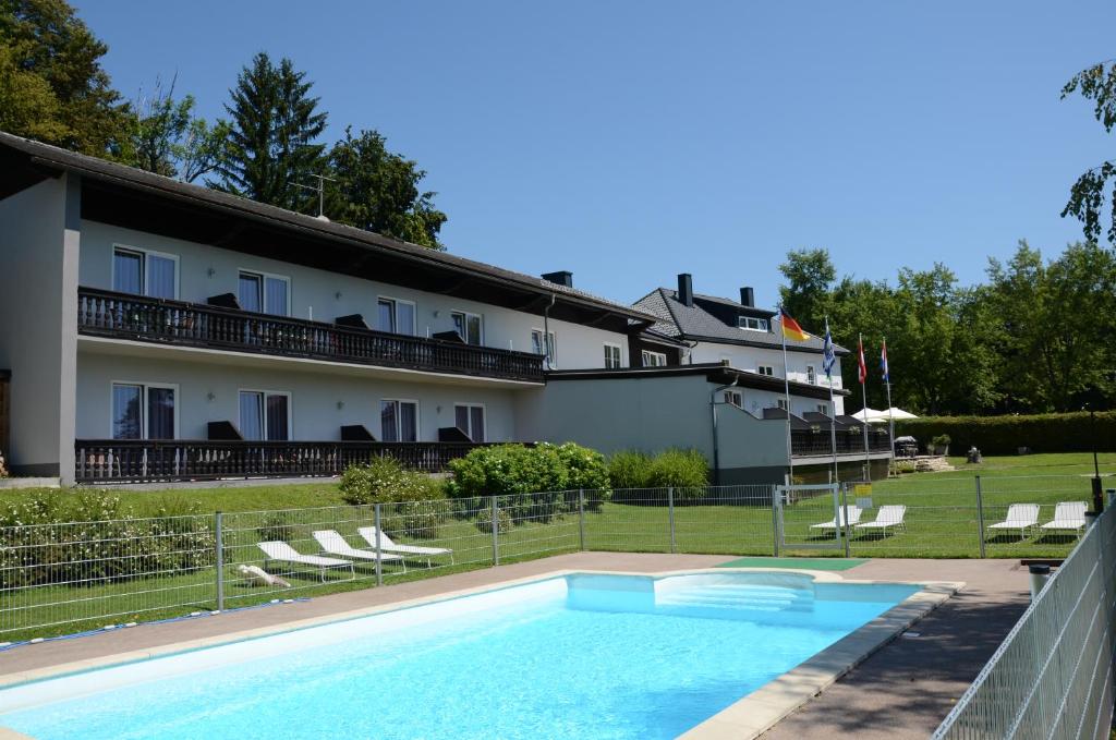 a hotel with a swimming pool in front of a building at Pension Hoogerland in Velden am Wörthersee