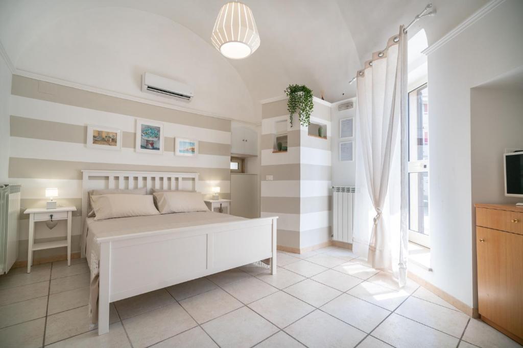 um quarto com uma cama branca e uma televisão em Mestmiché by Polignando em Polignano a Mare
