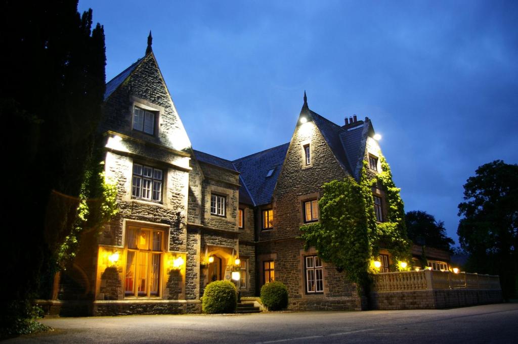 una vieja casa de piedra por la noche con luces en Maenan Abbey Hotel, en Llanrwst