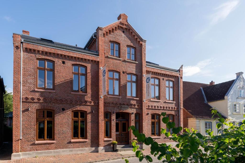 un antiguo edificio de ladrillo rojo con ventanas negras en Wellenreiter en Tating