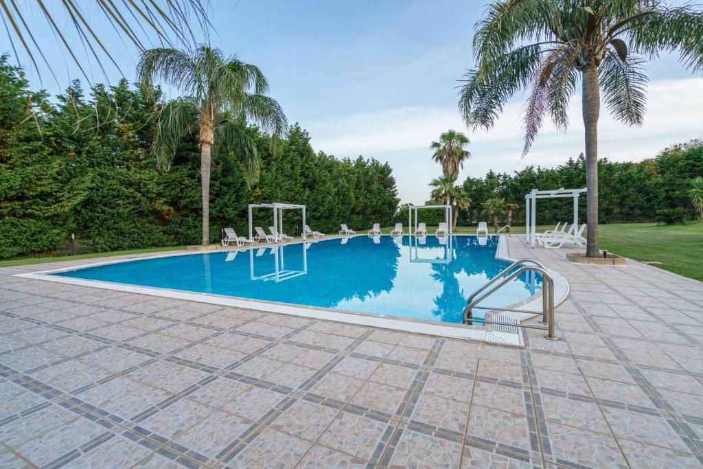 a large swimming pool with chairs and palm trees at Agriturismo Serafina in Otranto