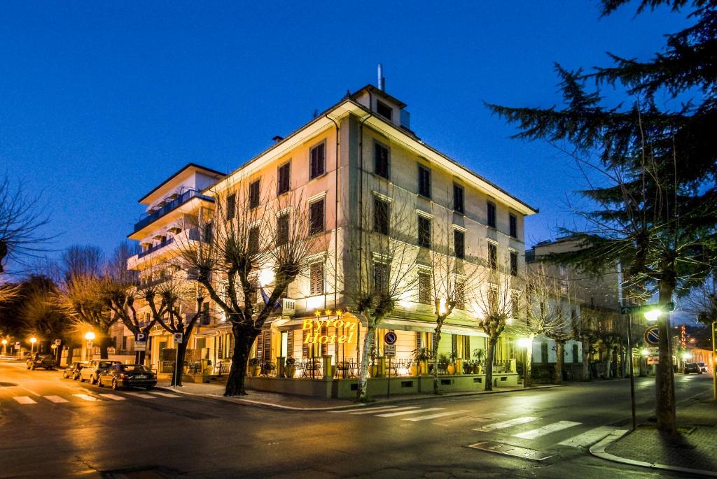 un grand bâtiment situé dans une rue de la ville la nuit dans l'établissement Hotel Byron, à Montecatini Terme