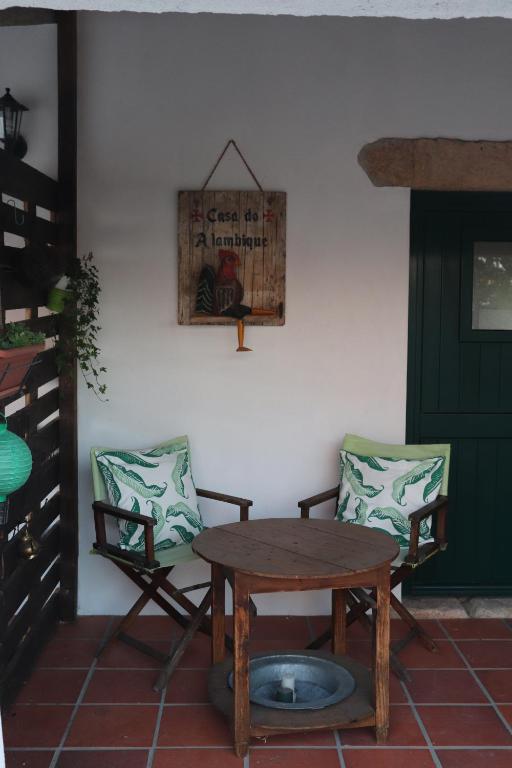 a wooden table and two chairs and a table and a door at Casa do Alambique in Tomar