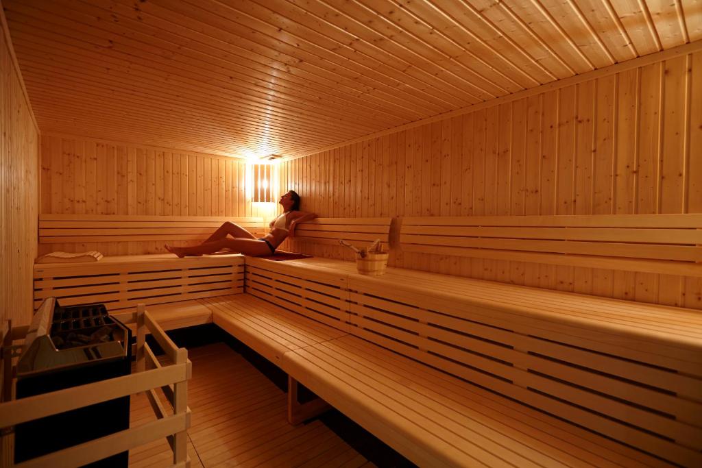 a woman is sitting in a sauna at The Cliff Bay - PortoBay in Funchal