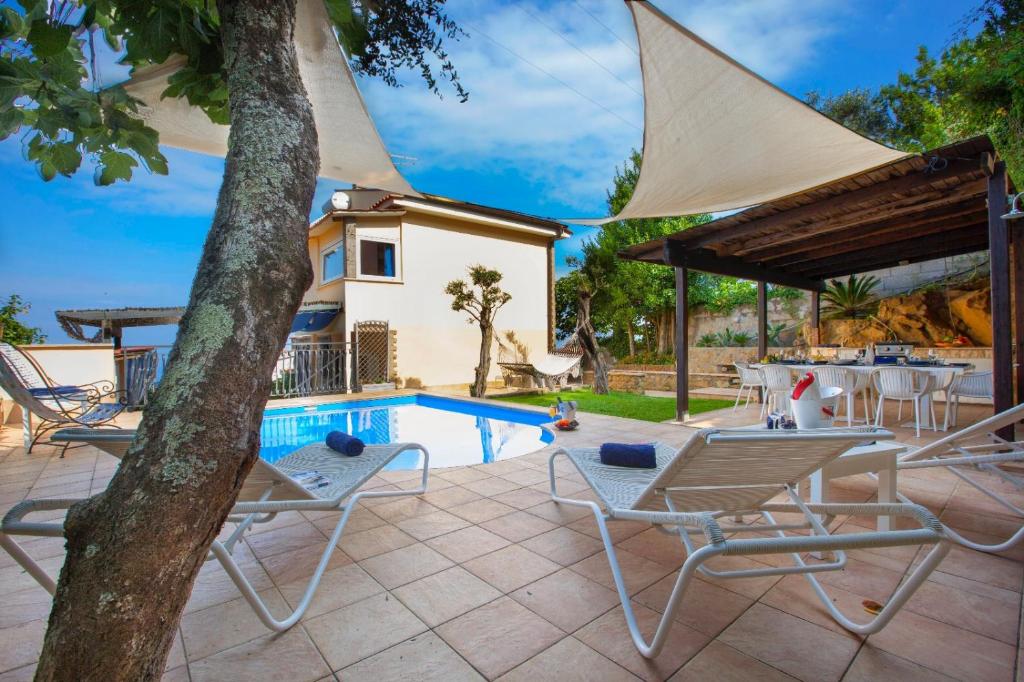 un patio con mesa, sillas y piscina en Villa Ieisha en Massa Lubrense