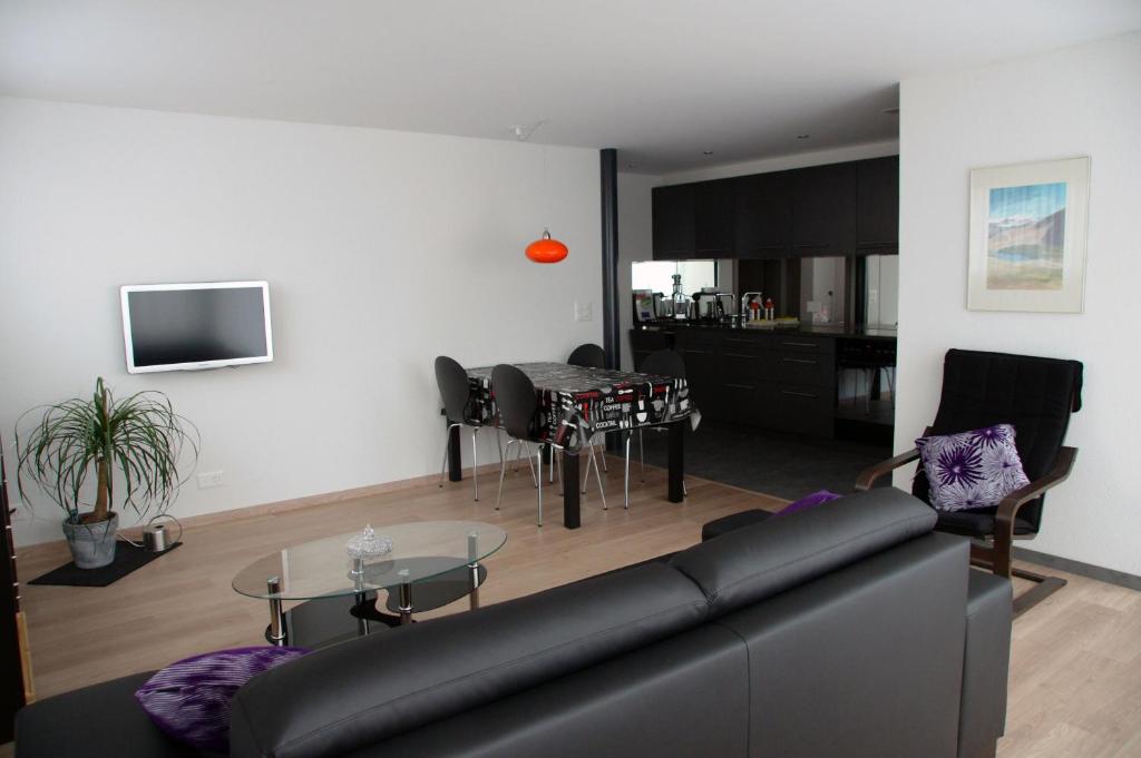 ein Wohnzimmer mit einem schwarzen Sofa und einem Tisch in der Unterkunft Apartment Gornerhaus in Grindelwald