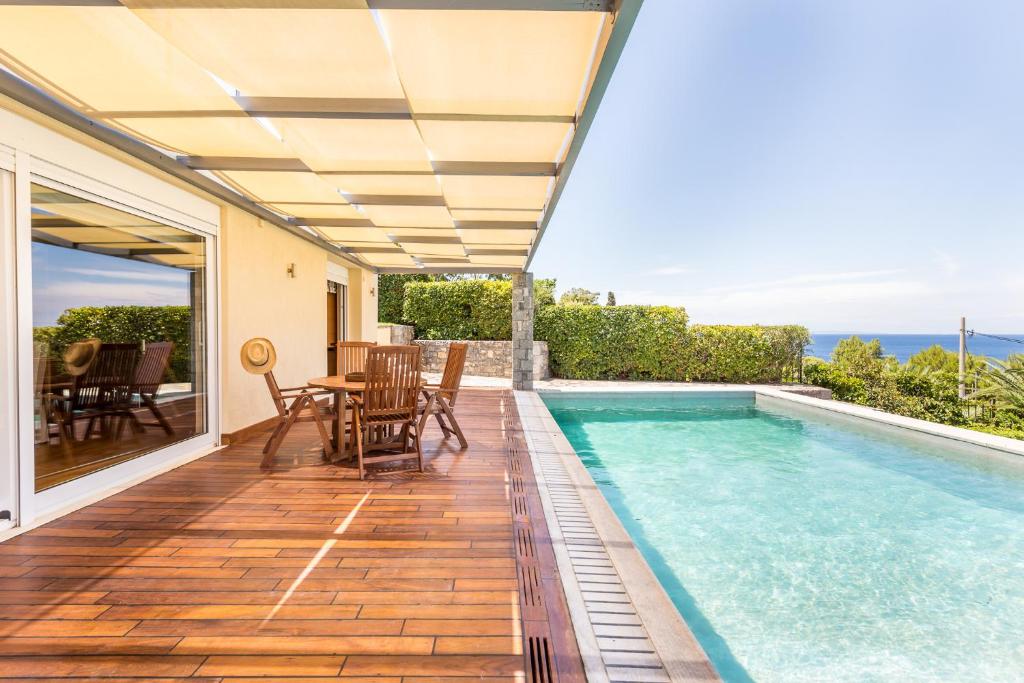 eine Terrasse mit einem Pool, einem Tisch und Stühlen in der Unterkunft Analisa Luxury Villa in Kap Sounion