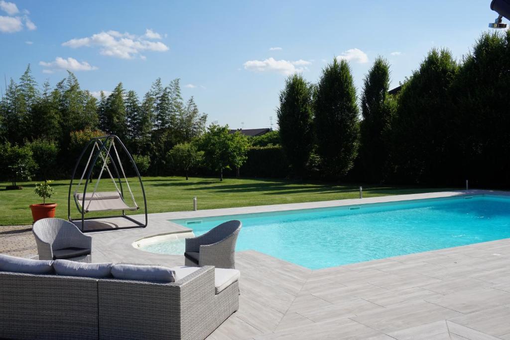 una piscina con 2 sillas y un columpio en Residence Le Palme en Torrazza Piemonte
