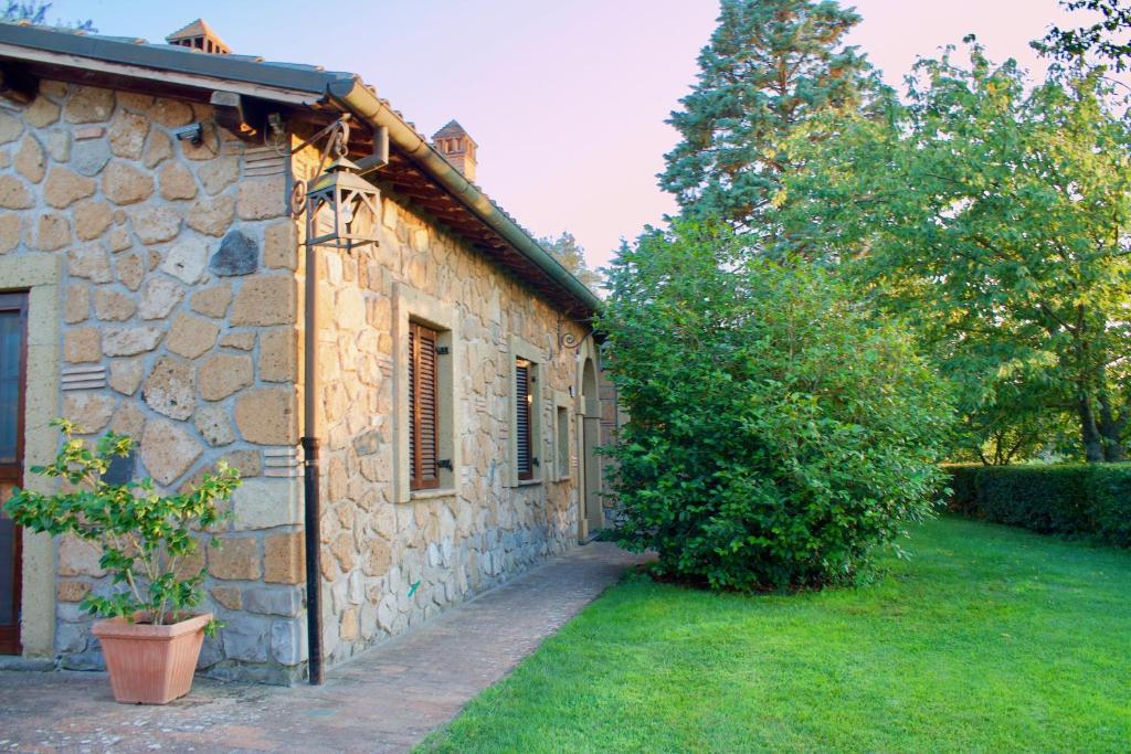a stone building with a tree next to a yard at Agriturismo Podere Pescara in Orvieto