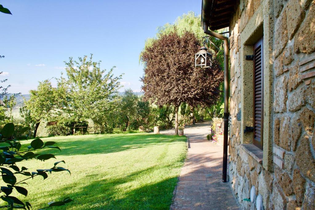 a stone house with a grass yard next to a building at Agriturismo Podere Pescara in Orvieto