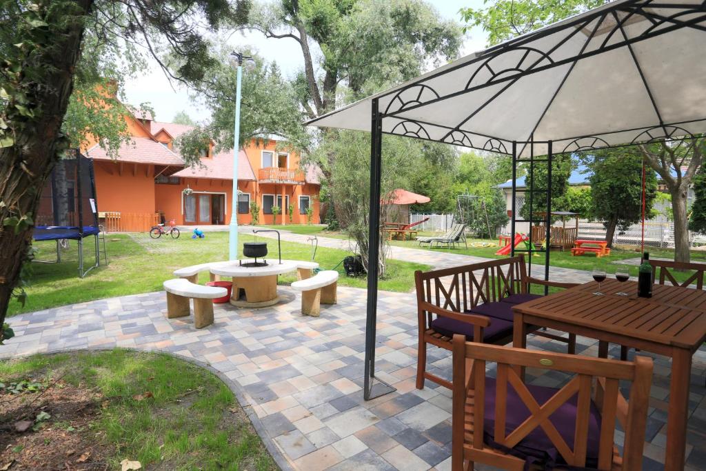 a patio with a table and benches and an umbrella at Holiday House Siófok in Siófok