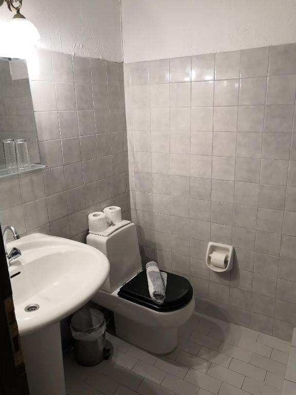 a bathroom with a white toilet and a sink at Arilla Beach Hotel in Perdika