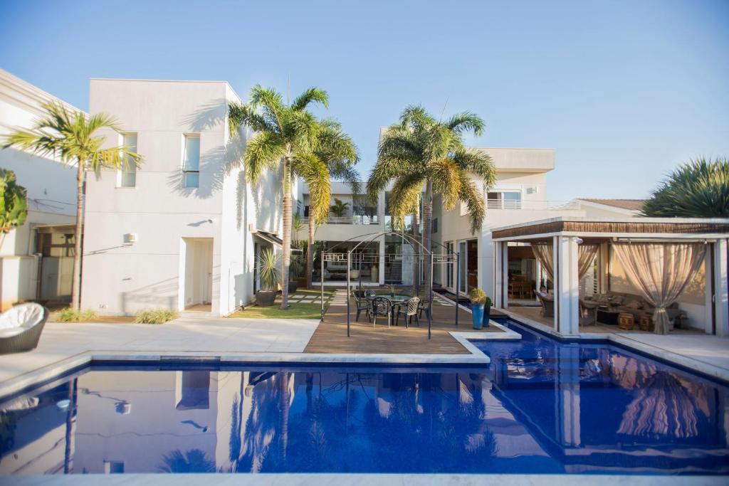 a swimming pool in front of a house with palm trees at Suite casa de luxo in Campinas