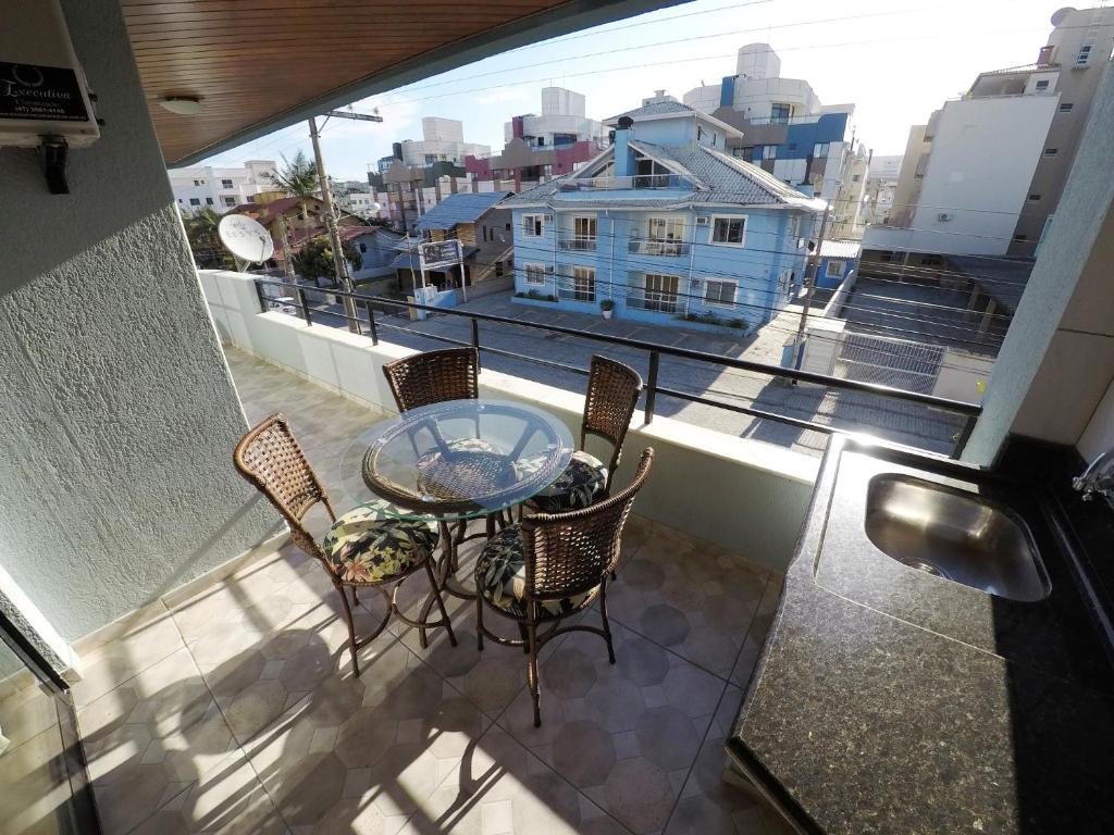 balcón con mesa, sillas y ventana en Ed Karine Praia de Bombas, en Bombinhas