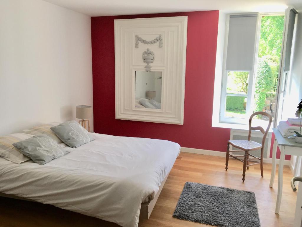 1 dormitorio con pared roja, cama y mesa en Les Escuries, en Commes
