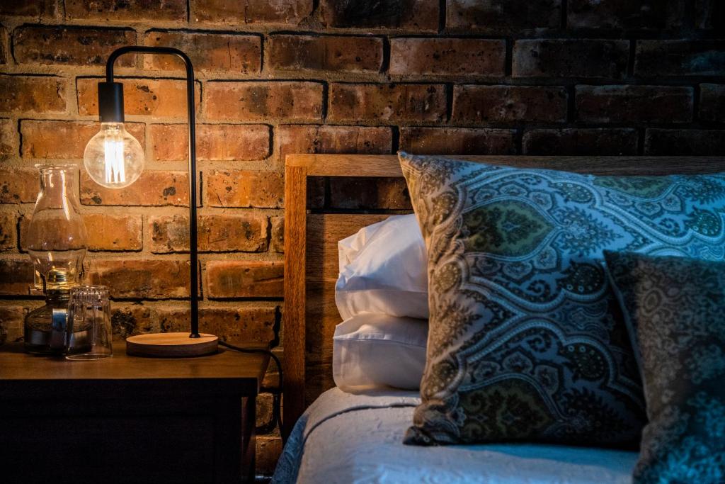 a bedroom with a bed with a lamp and a brick wall at Tarry-Stone Cottages in Dullstroom