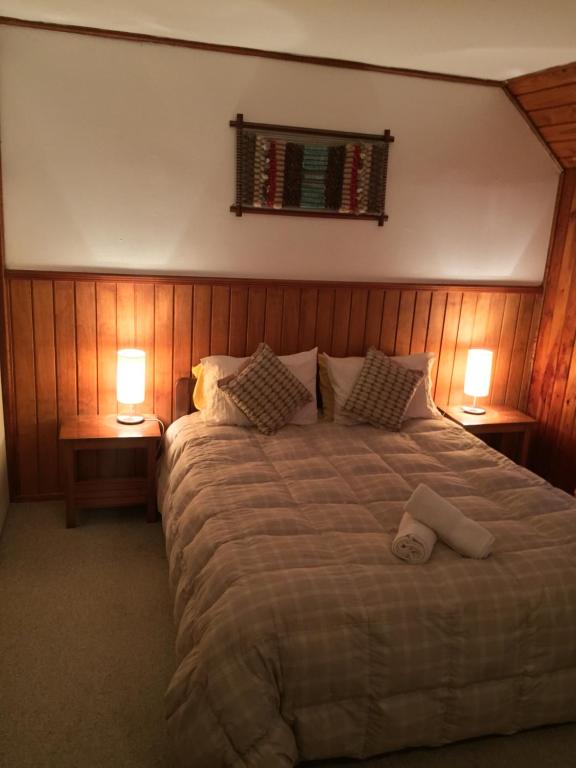 a bedroom with a large bed with two lamps at Hostería Bilbao in Villarrica