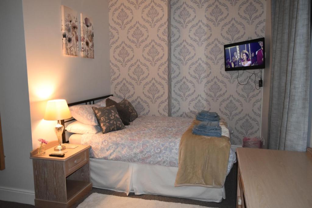 um pequeno quarto com uma cama e uma mesa de cabeceira em Adelaide Apartments 2 em Blackpool