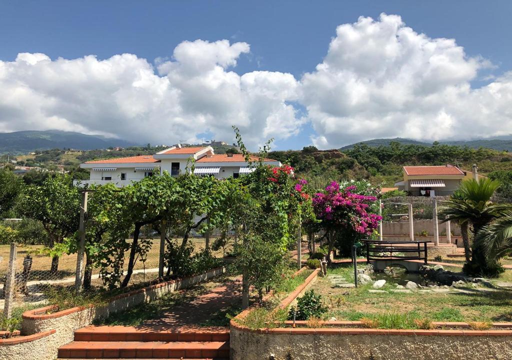 a garden with trees and flowers in front of a house at Casa Vacanza Demetra in Marina di Fuscaldo