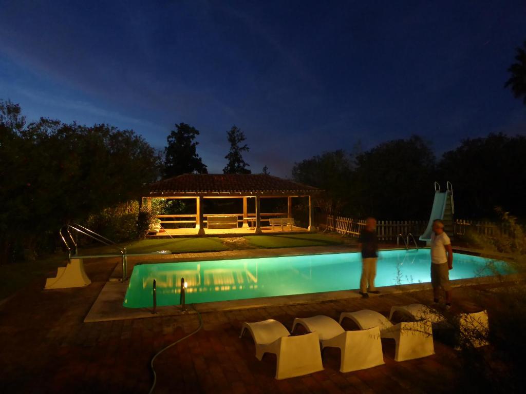 a man standing next to a swimming pool at night at Quinta do Mourão in Tentúgal