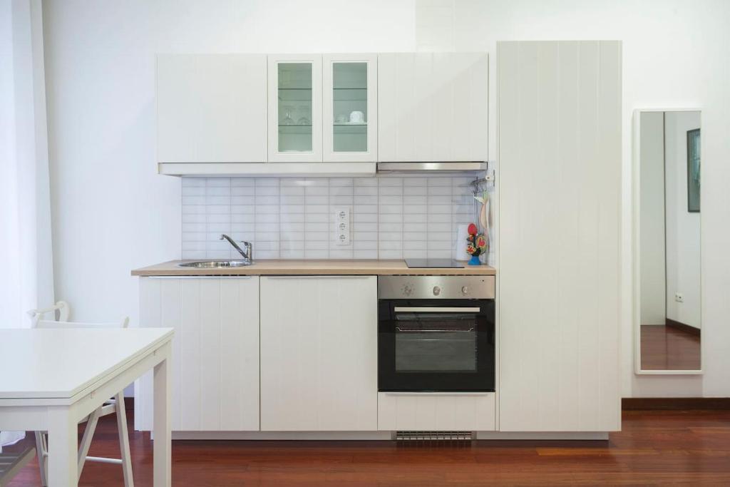 uma cozinha com armários brancos e um lavatório em Flores Studio no Porto