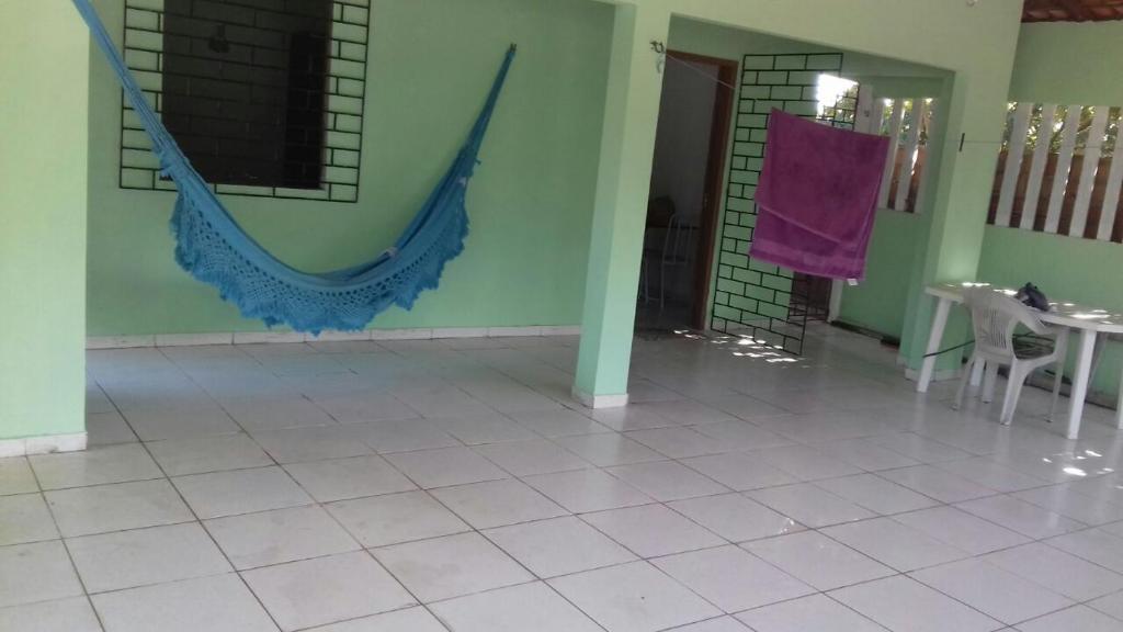 a room with a tiled floor with a table and a hammock at Casa de Veraneio in Salinópolis