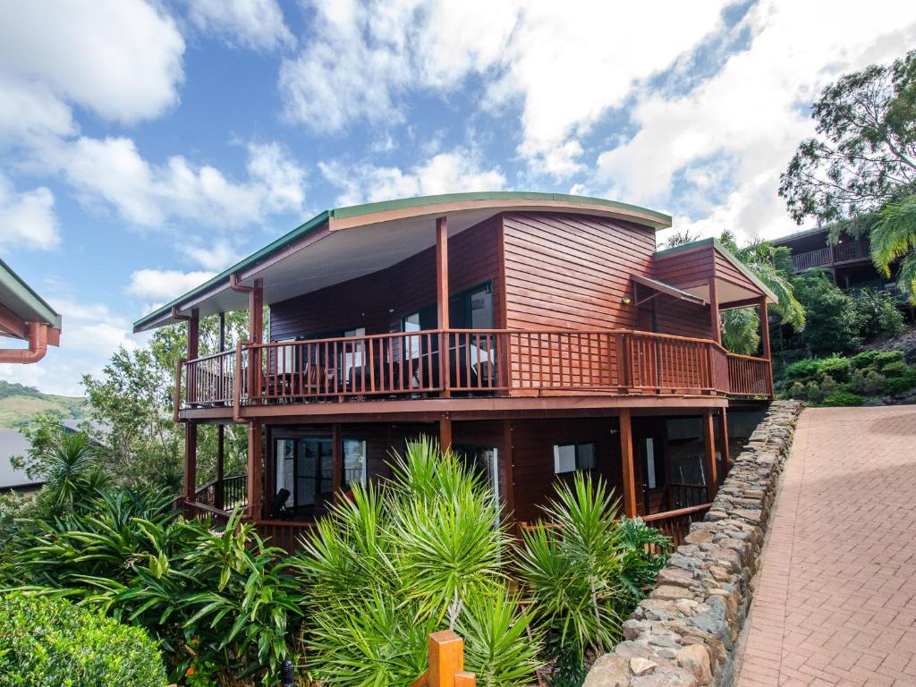 a large wooden house with a balcony on a hill at Casuarina Cove 1 on Hamilton Island by HamoRent in Hamilton Island