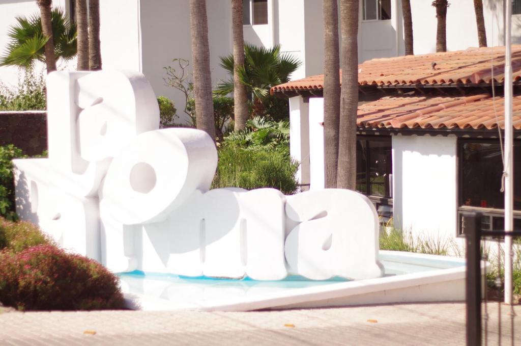 una gran señal blanca frente a un edificio en La Paloma Beach&Tennis Resort, en Rosarito