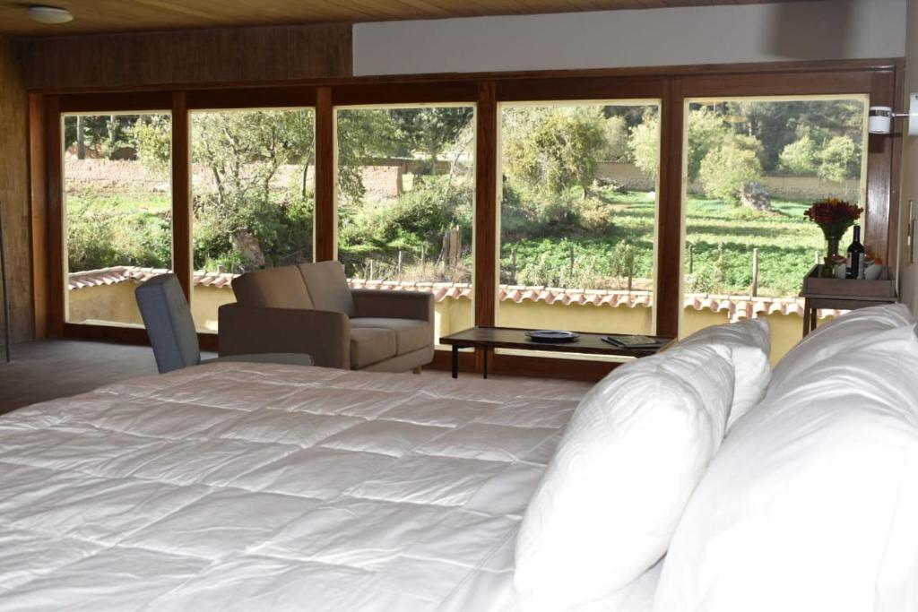 a bedroom with a white bed and a large window at Casafranca in Ollantaytambo