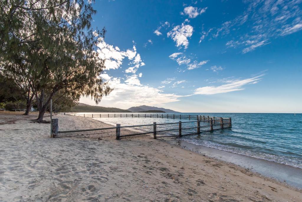 a wooden fence on a beach near the water at Birdsong House- Dingo Beach in Hideaway Bay